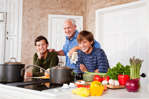 Father and teenage sons in kitchen by stove